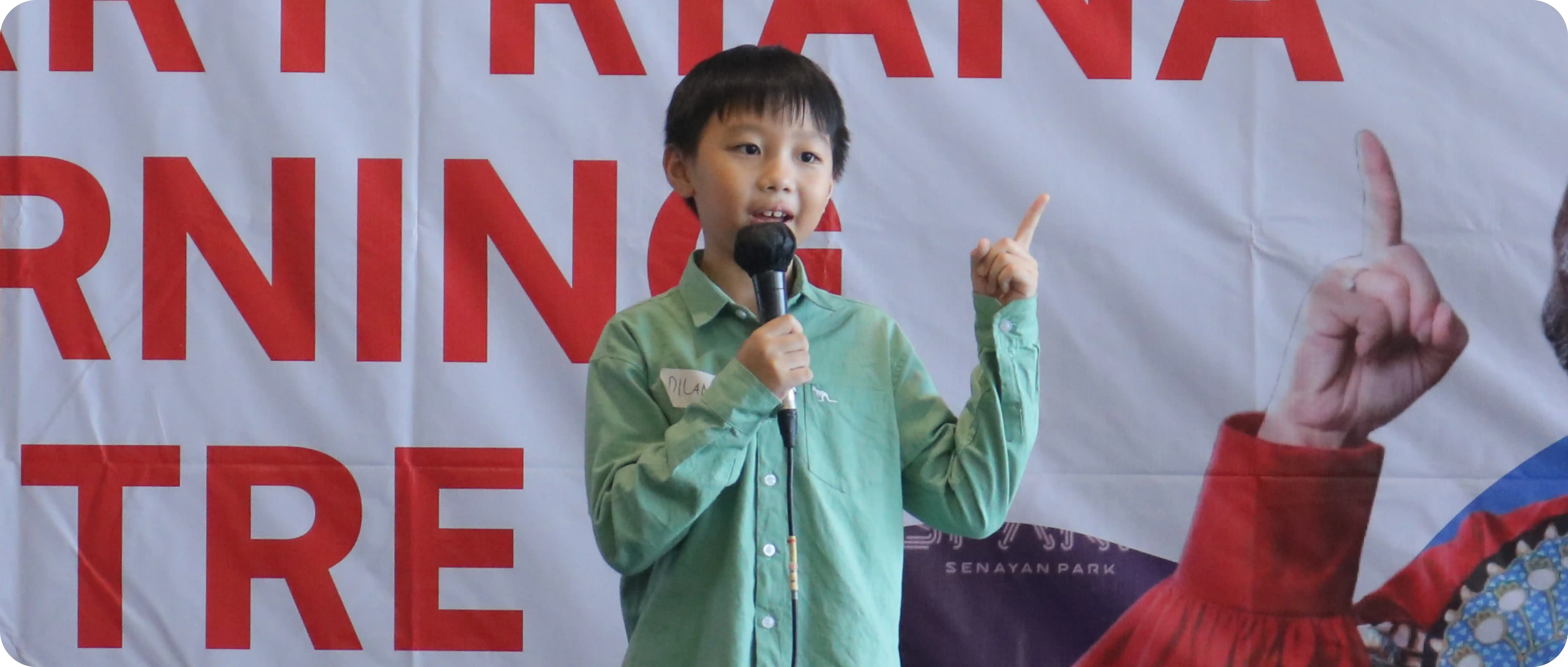 Anak laki-laki berbicara di depan umum menggunakan mikrofon